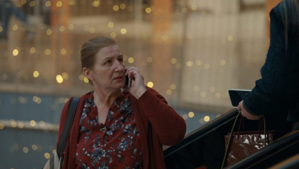 IFRR Honey Bunny film still: Woman on phone, escalator. "Krakatoa, Honey Bunny, The Killing of Meghnad" at IFFR 2026.