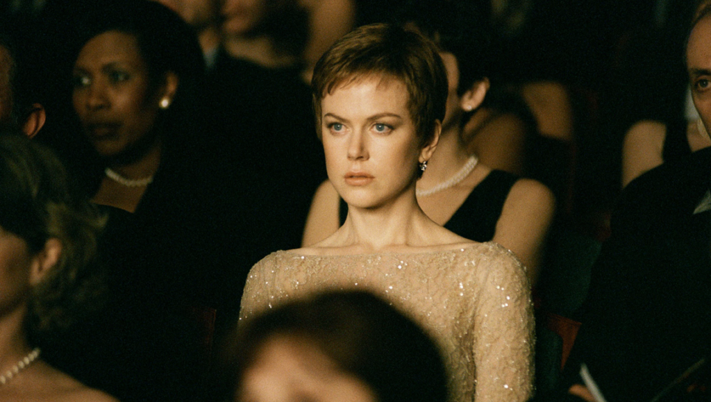 Birth movie image: Nicole Kidman attends an event, surrounded by an audience, gazing intently. Birth film still.