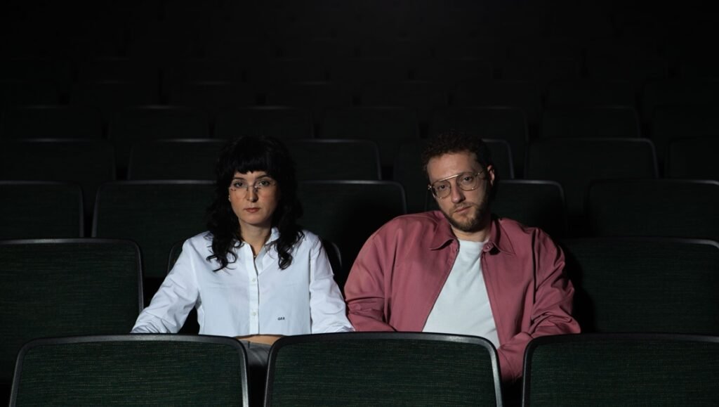 The Humor Amplifies The Horror: Daniel Goldhaber & Isa Mazzei On Faces Of Death Daniel Goldhaber and Isa Mazzei, creators of 'Faces of Death,' in a theater setting. Horror film discussion.