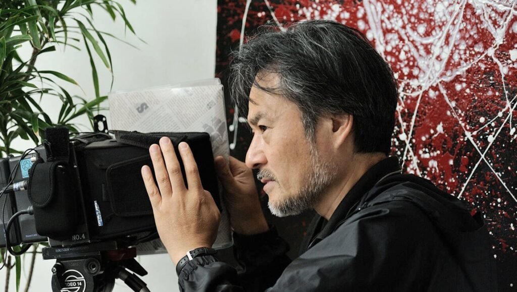 Kiyoshi Interview: Close-up of a filmmaker operating a professional video camera, focusing on capturing the interview.