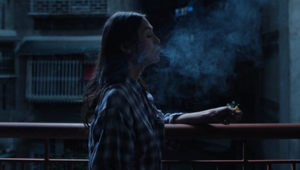 Isabel Sandoval, cinematic profile on balcony, exhaling smoke. Art and film concept.