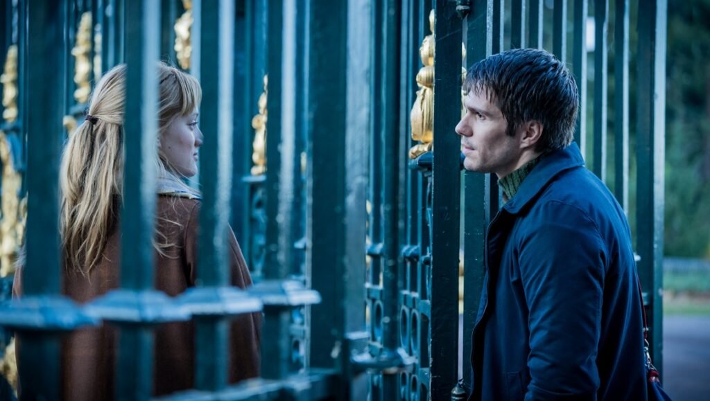 Two Pianos film scene: A man and woman face each other through an ornate gate. Arnaud Desplechin film.