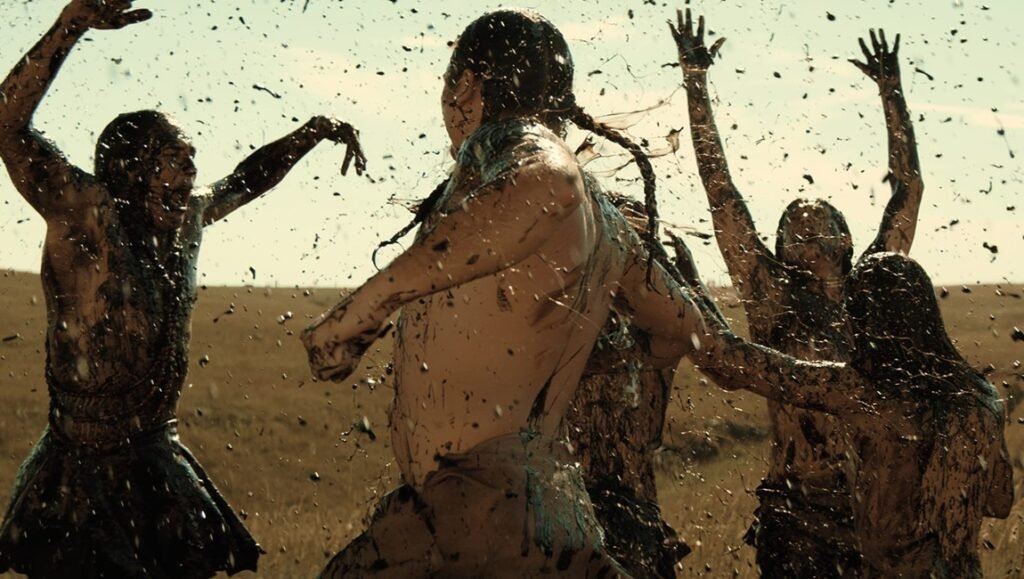 Lily Gladstone interview: Indigenous people covered in mud during a ritualistic scene.