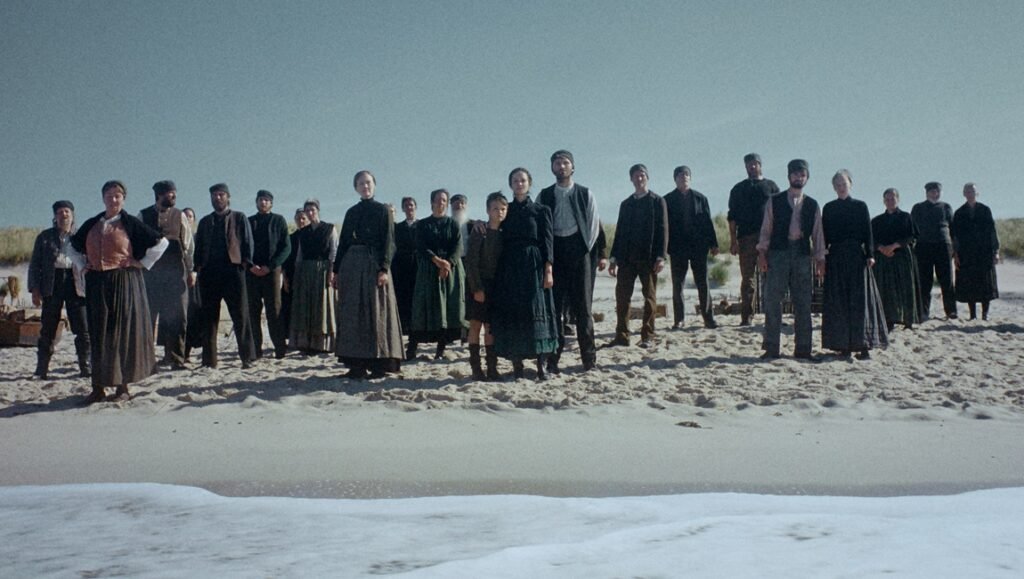 Trial of Hein movie scene: Group of villagers stands on a beach, facing forward, in traditional 1926 attire.