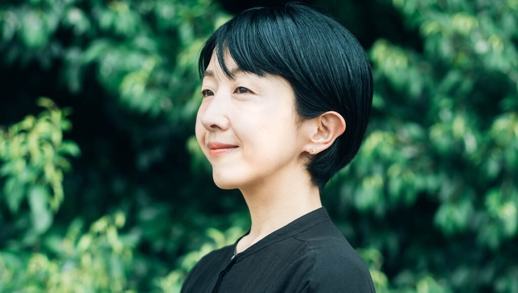 Growing Pains: A Conversation with Chie Hayakawa on Renoir Chie Hayakawa smiles in profile against a background of green foliage.