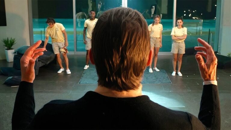 Person with raised hands facing four people in yellow shirts and khaki shorts.