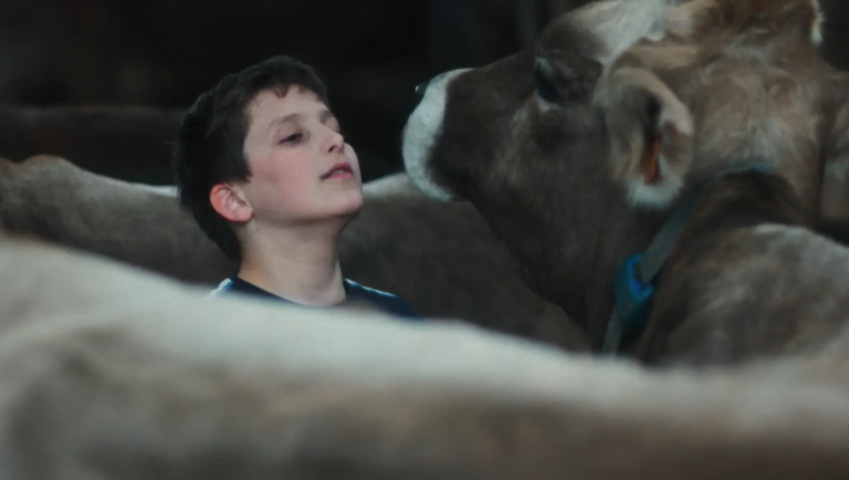 Gabin movie scene: Boy looking up at a cow, evoking themes of youth and rural life. Cannes '26 review.