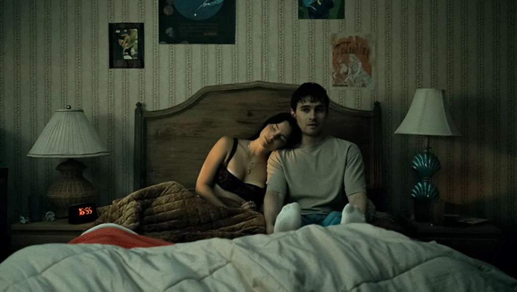 Curry Barker Interview: Couple in bed, woman asleep on man's shoulder, bedroom scene. Intimate moment review.