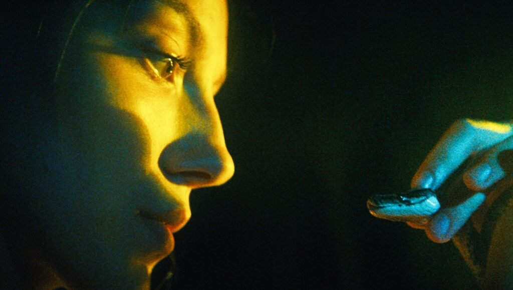 The Python Hunt movie still: Close up of woman looking at a snake, film review by Xander Robin.
