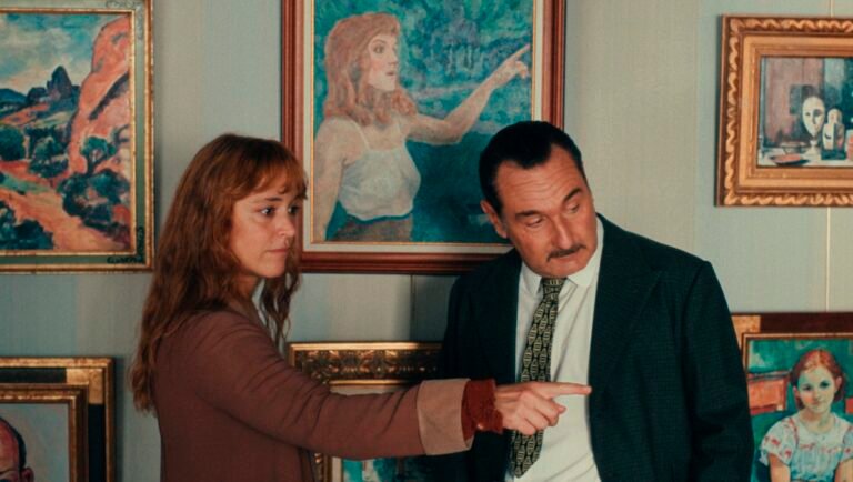 Man and woman pointing at paintings in an art gallery, discussing portrait art and landscape art. Gallery wall filled with art.