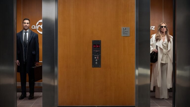 A man in a dark suit and a woman in a white coat stand in separate elevators with wood-paneled walls.