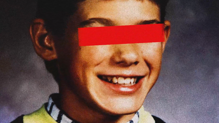 Grainy school portrait of a grinning boy with a vibrant red horizontal bar obscuring his eyes.