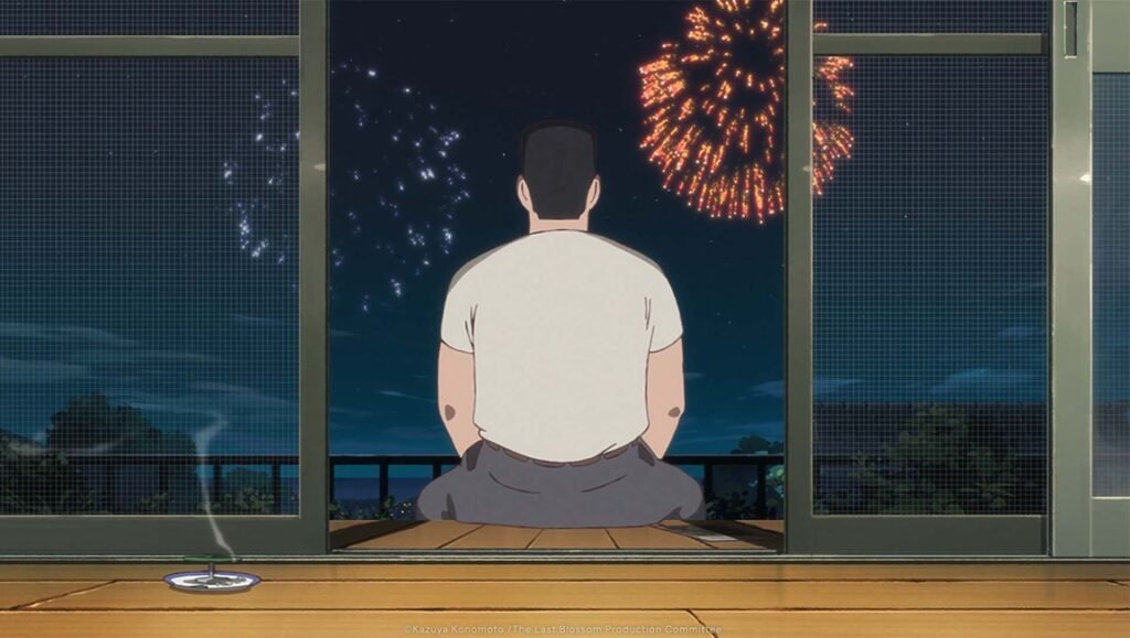 Man sits on a porch at night watching orange and white fireworks through an open sliding door.
