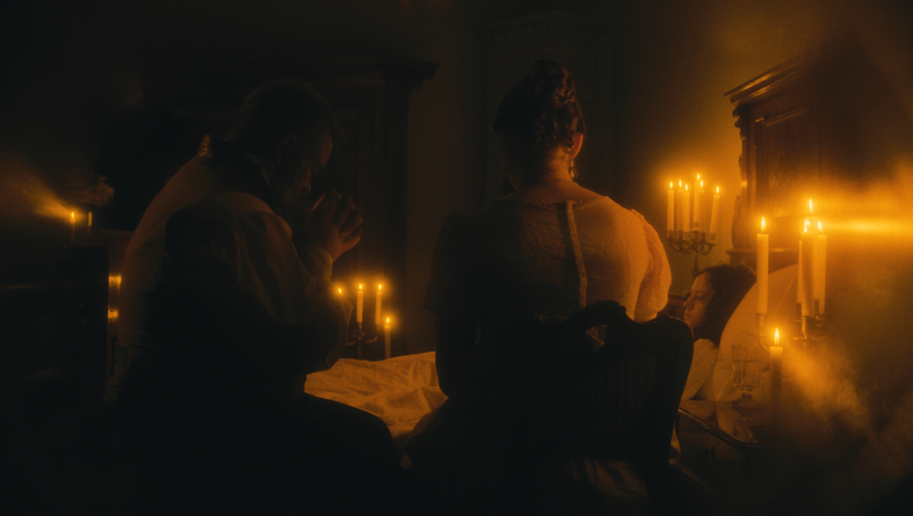 Fantasia Fest 2026 — Dispatch 2: Colony, Someone\’s Daughter, Godhead Man and woman sit in a dimly lit room, illuminated by warm candlelight, attending to a person lying in bed.