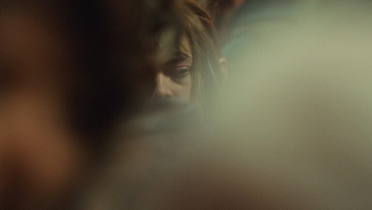 Close-up of a person with tired eyes partially obscured by a soft, glowing haze.