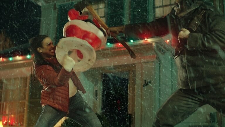 Woman in a red puffer jacket blocks an axe-wielding attacker with a plastic Santa Claus decoration during a snowstorm.