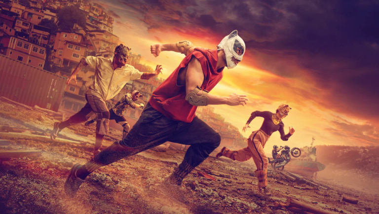 People in animal masks and athletic gear run across a dusty wasteland against a dramatic sunset sky.