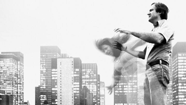 Man gesturing toward a blurred, ghostly figure against a backdrop of a city skyline at night.