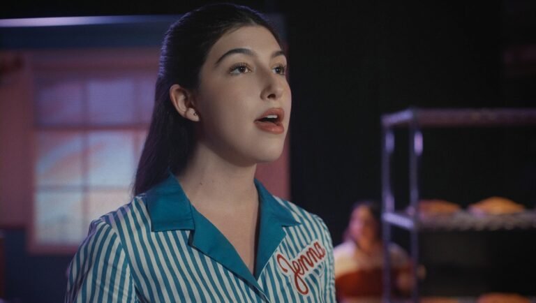 Young woman named Jenna wearing a blue and white striped uniform with her name embroidered in red script.