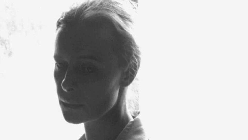 Close-up of a woman in high-contrast black and white, her face partially silhouetted against a bright background.