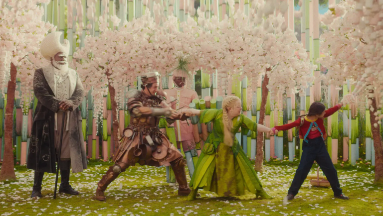 Characters in elaborate costumes stand in a whimsical forest filled with pastel-colored trees and falling blossoms.