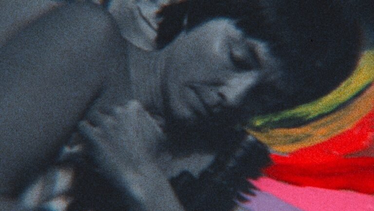 Close-up of a person with dark hair sleeping beside vibrant, multicolored fabric stripes.