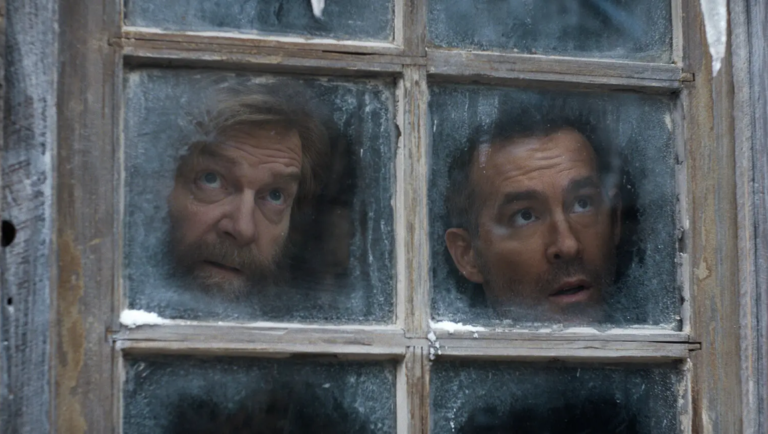 Two men with concerned expressions peer through the frosted panes of an old wooden window.