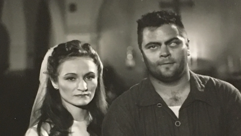 Fragments of Musclefest 2026: Before This Bomb Explodes Again Black-and-white film still of a veiled woman beside a burly man in a dark shirt, both gazing forward.