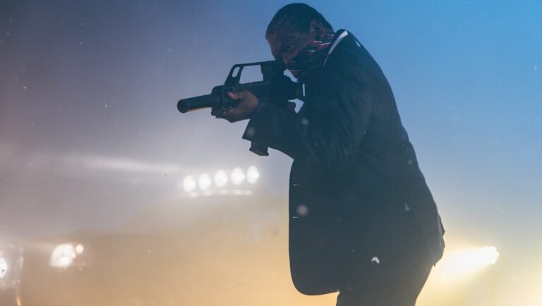 Man in a suit aiming a rifle in foggy blue light
