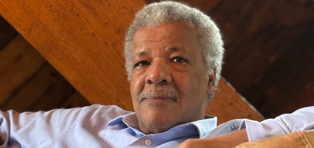 The World Was Just Happening: A Conversation with David Greaves on Once Upon a Time in Harlem David Greaves with grey hair and moustache reclining indoors against wooden beams.