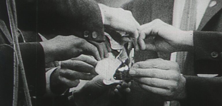 Hands holding a burning draft card during a 1966 protest, with flames consuming the paper.