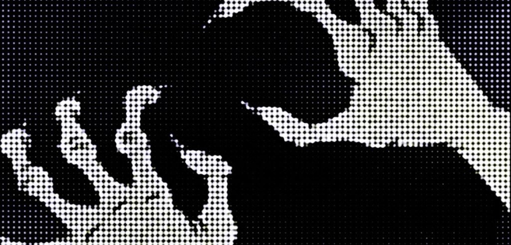 High-contrast pixelated black and white hands reaching toward each other against a dark dotted background