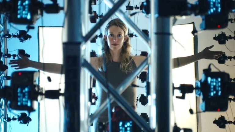 Woman stands with arms outstretched inside a metal truss surrounded by glowing blue cameras.